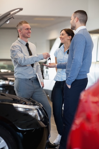 Salesman giving car key to a couple