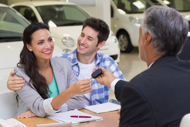 Photo salesman giving car keys to a couple