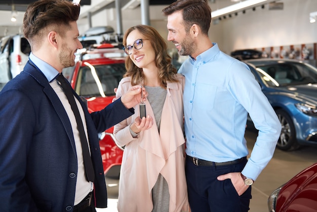 Salesman handing couple brand new car keys