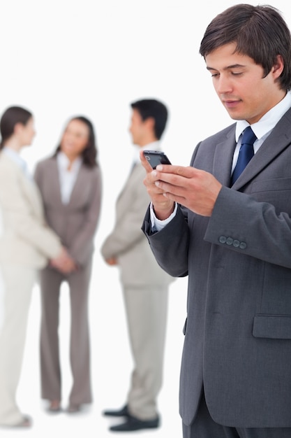 Salesman reading text message on cellphone with team behind him