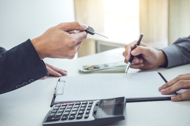 Salesman send key to customer after man signing car document contract good deal