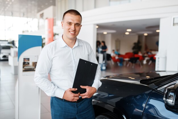 Salesman shows new car in showroom.