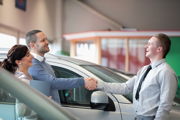 Photo salesman smiling while shaking the hand of a customer