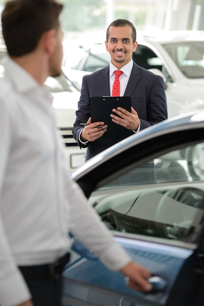 Salesman standing in the dealership and helping a client.