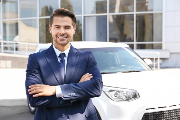 Salesman standing near new car outdoors