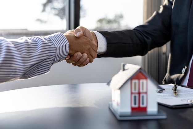 The salesperson of the housing estate in the project and the\
customer shake hands after successfully signing the contract.\
concept of selling housing estates and real estate.