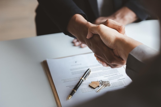 The salesperson of the housing estate in the project and the customer shake hands after successfully signing the contract Concept of selling housing estates and real estate