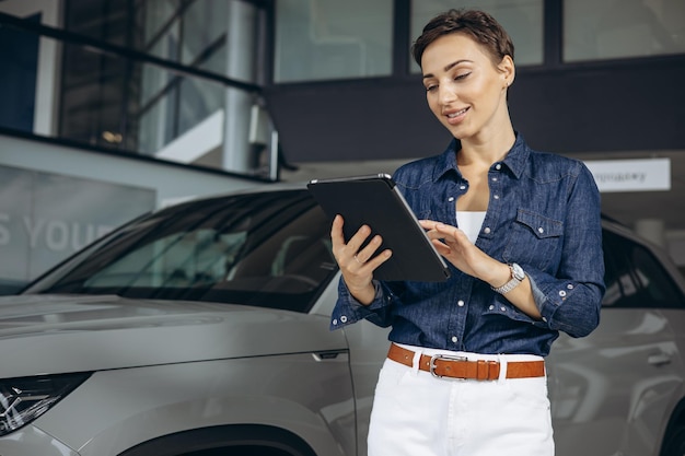 Saleswoman at car showroom selling a car