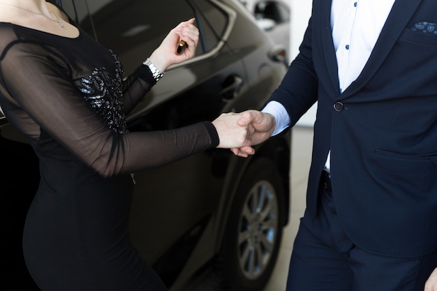 saleswoman giving car keys to new owner