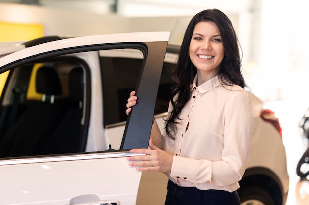 Saleswoman with key present a new car in dealership center