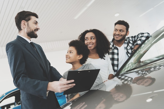 Photo sallesman showing a car to a family