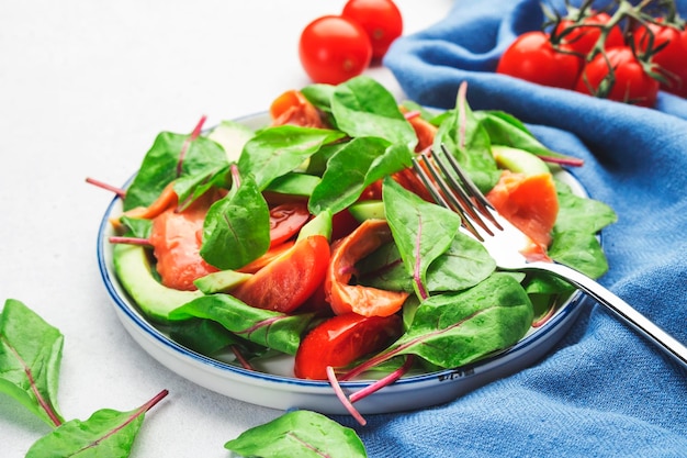 Salmon avocado salad beet leaves radicchio tomatoes lemon and
olive oil dressing for keto and low card diet gray background top
view