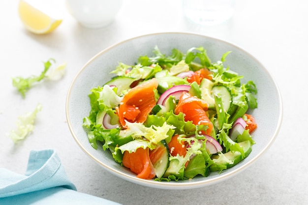 Salmon avocado salad with salted fish lettuce red onion and cucumbers