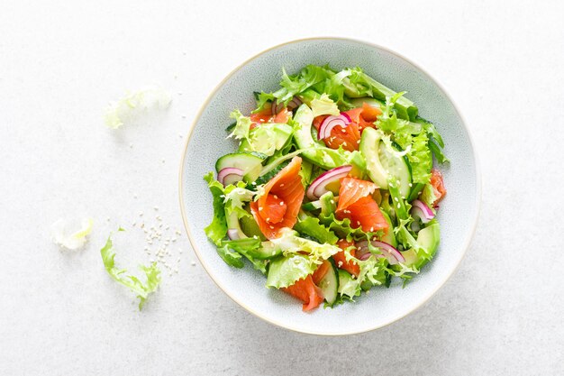 Salmon avocado salad with salted fish lettuce red onion and cucumbers