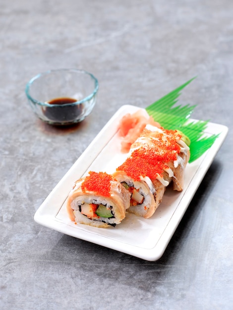 Salmon Blaze Sushi Roll, Crab Stick, Cucumber, and Roast Salmon Topped with Tobiko. Served on White Rectangular Plate.