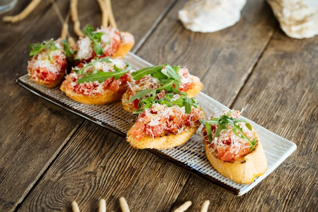 Salmon bruschettas with grated cheese and arugula