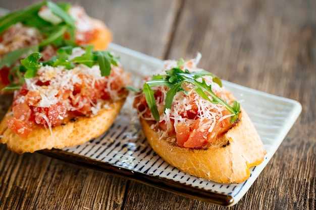 Salmon bruschettas with grated cheese and arugula