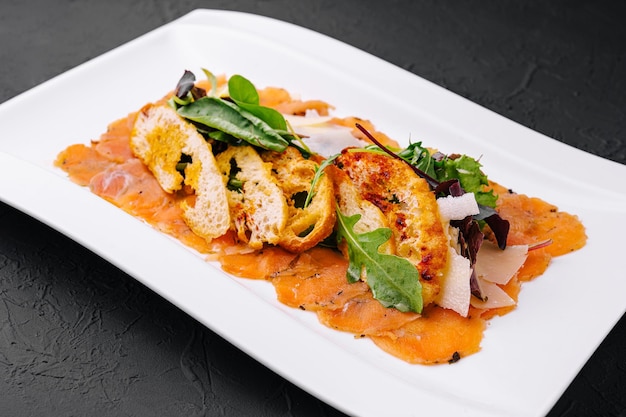 Salmon carpaccio served with toast on plate