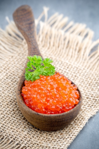 Salmon caviar with spoon on gray background