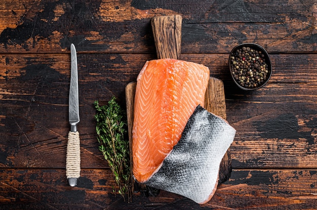 Salmon fillet fish on a wooden board with herbs and salt