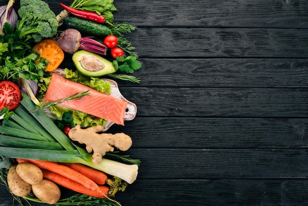 Salmon fillet and fresh vegetables healthy food on a black\
wooden background healthy food top view copy space