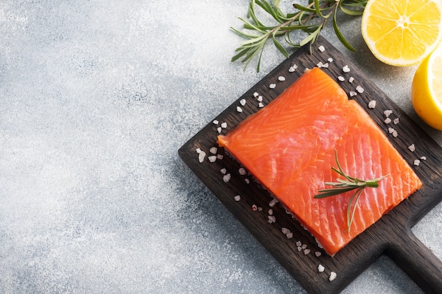 Salmon fillet, red salted fish on a wooden chopping Board. Lemon, rosemary spices. Copy space.