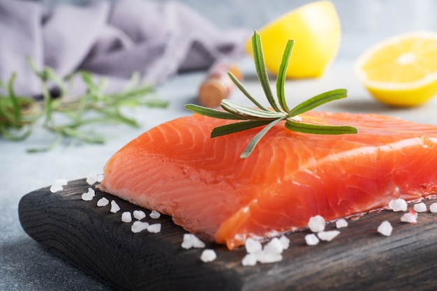 Salmon fillet, red salted fish on a wooden chopping Board. Lemon, rosemary spices.