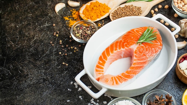 Salmon fillet with aromatic herbs spices and vegetables on a dark background