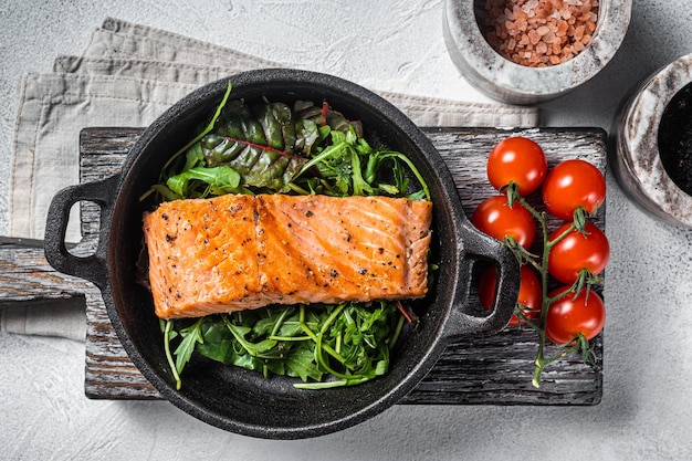 Salmon fillets grilled steaks in skillet with herbs White background Top view