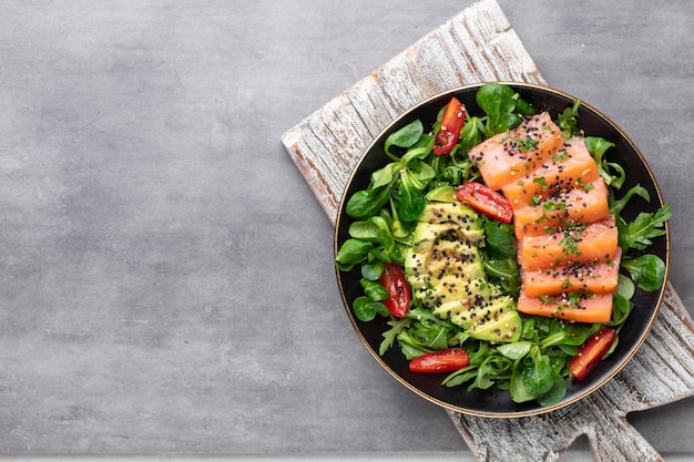 Salmon fish fillet with fresh salad, avocado top view.