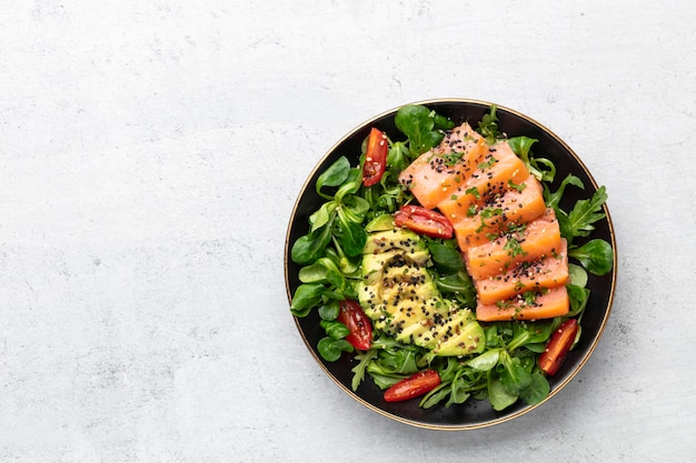 Salmon fish fillet with fresh salad avocado top view