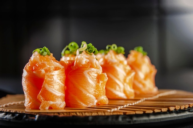 Salmon Jhow sushi on bamboo mat in a black plate. Closeup.