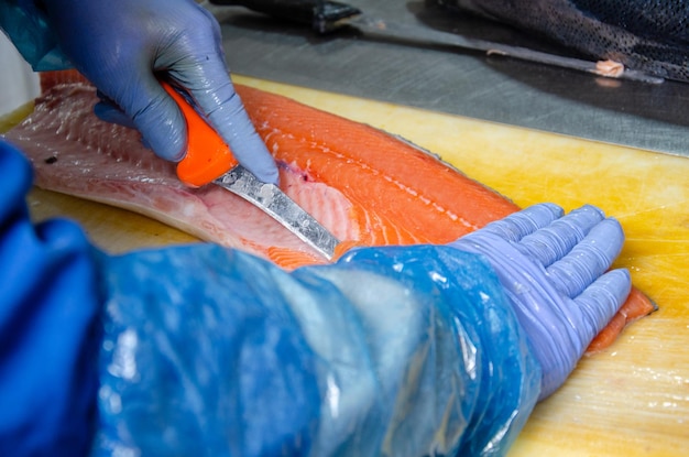 Foto salmone un uomo taglia un pesce salmone mangiare sano salmone rosso foto sulla produzione di pesce