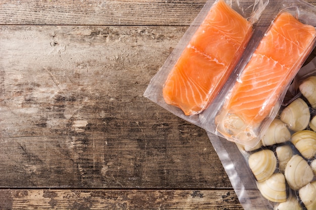 Salmon packaged in plastic on wooden table, top view, copy space