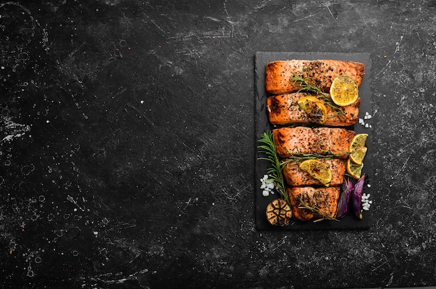 Salmon Pieces of grilled fish on a black stone background Recipe Seafood Free space for text