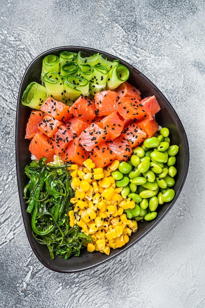 Salmon Poke bowl with Cucumber Edamame and Rice White background Top view