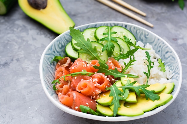 Salmon poke with avocado, arugula and cucumber in a bowl