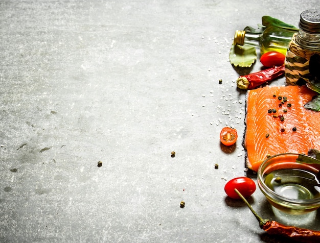 Salmon raw fillet with tomatoes, olive oil and spices. On a stone background.