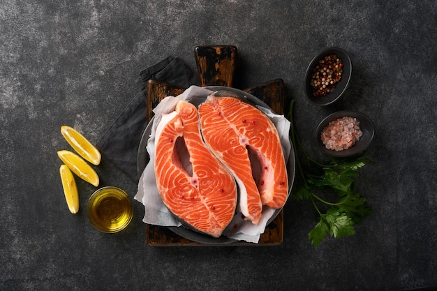 Salmon Raw salmon steak Fresh raw salmon fish with cooking ingredients herbs and lemon prepared for grilled baking on black background Healthy food Top view Copy space