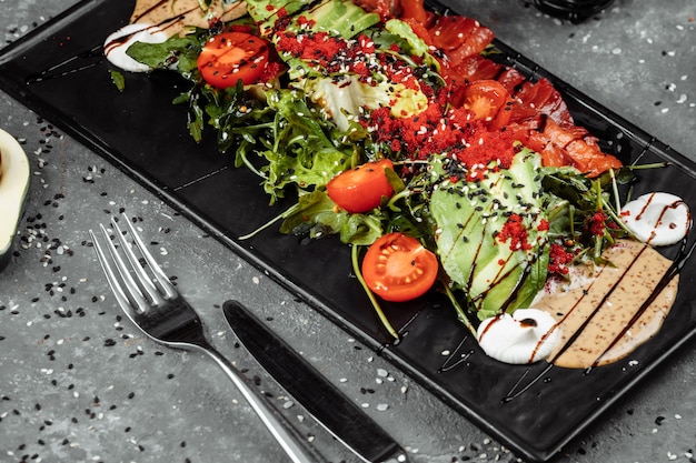 Salmon salad gravlax. Smoked salmon salad, with mixed greens, cherry tomatoes, avocado, black olives, carrots, sprouts, cucumber, and lime. Delicious healthy eating