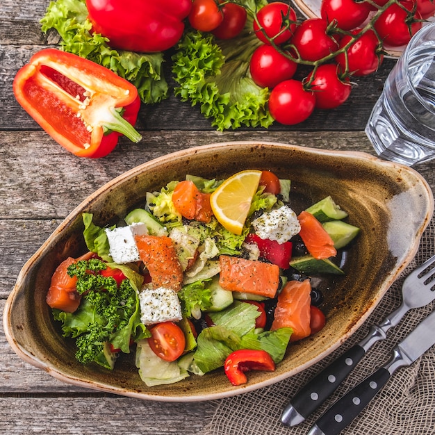 Salmon salad with red pepper, cherry tomatoes, salad, cheese, cucumber and black olives. Concept for a tasty and healthy meal. Top view. Closeup