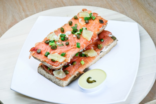 Salmon sandvich on white plate.