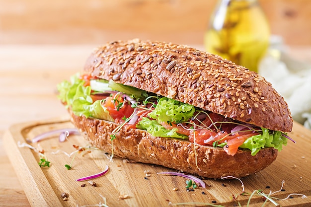 Salmon sandwich - smorrebrod with cheese cream and microgreen on wooden table.