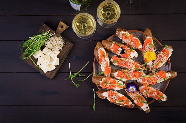 Salmon sandwiches with cream cheese and microgreen on wooden table. 