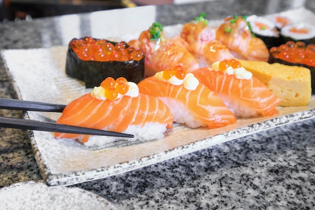 Набор суши-роллов с лососем и сашими с палочками на тарелке Японская кухня