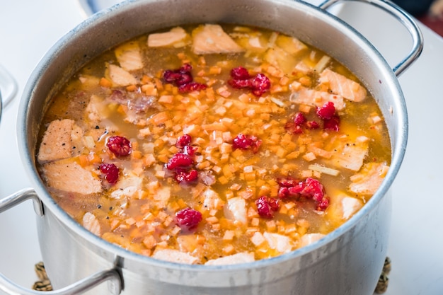 Foto zuppa di salmone con carota e lampone in pentola inossidabile di cibo tradizionale