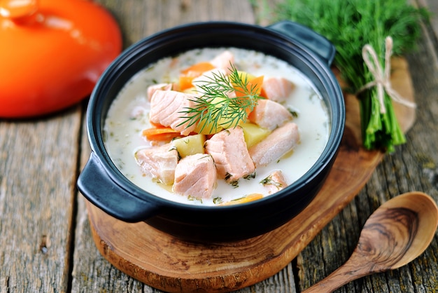 Salmon soup with cream on an old wooden background
