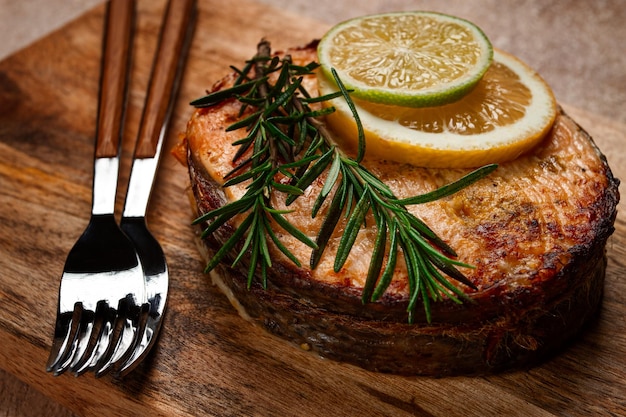 salmon steak fried on a cutting board top view rosemary lemon and lime homemade one serving