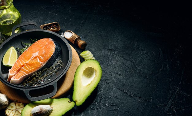 Salmon steak prepared for frying with ingredients on a dark background