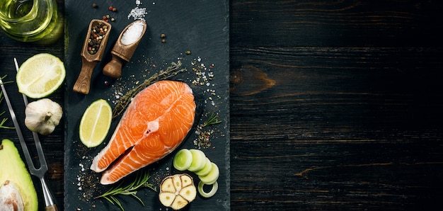 Salmon steak prepared for frying with ingredients on a dark background